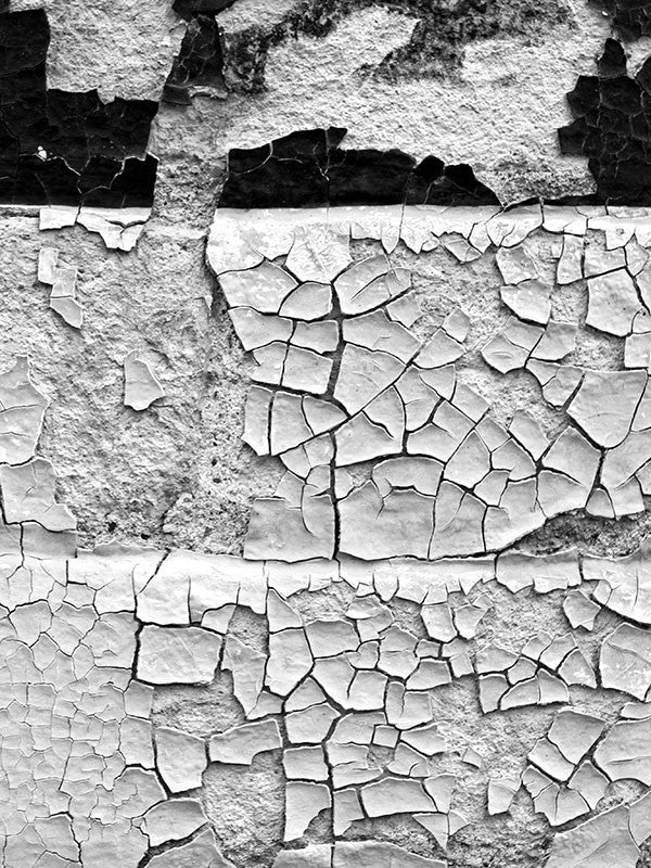 Black and white fine art photograph of a chips and flakes of paint on a brick wall in Miles City, Montana.