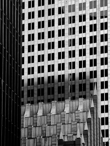 Black and white architectural photograph of the overlapping lines and grids of downtown Houston skyscrapers.