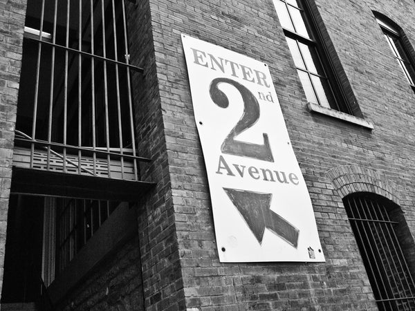 Black and white photograph of a sign on the Nashville waterfront that points the way to 2nd Avenue and the entertainment district.