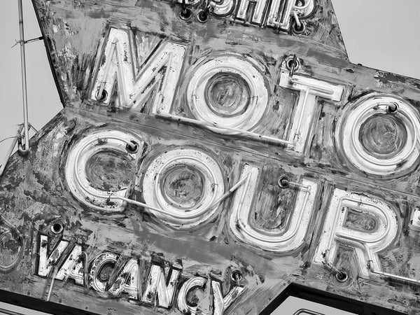Black and white detail photograph of a beautifully faded vintage motel neon sign. The fading colors have left a very painterly effect.