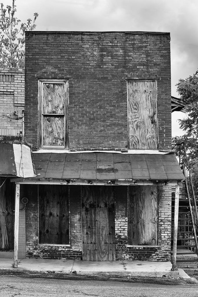 Black and white photograph of an abandoned brick storefront in the deserted downtown of Adams, Tennessee. Adams is famous as the home of the Bell witch legend.