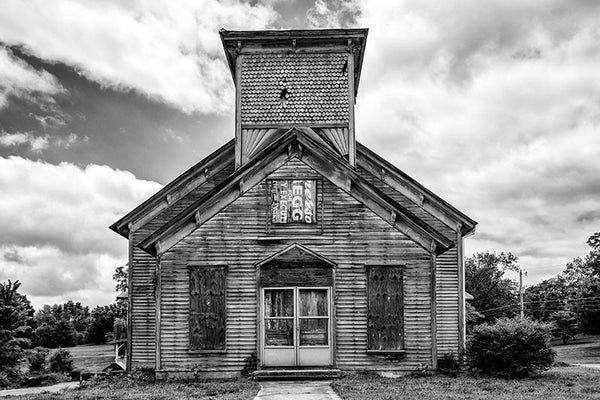 Black and white photograph of an abandoned and boarded-up church in the deserted former downtown of Adams, Tennessee. On the day this photograph was made, a mockingbird in the steeple was loudly protesting my presence.