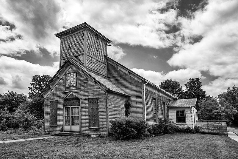 Black and white photograph of an abandoned and boarded-up church in the deserted downtown of Adams, Tennessee. On the day this photograph was made, a mockingbird in the steeple was loudly protesting my presence.
