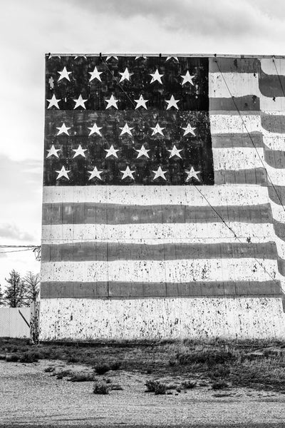 Black and white fine art photograph of a huge, hand-painted US flag on the outside of the Midway Drive-in Theater in the Texas Panhandle.