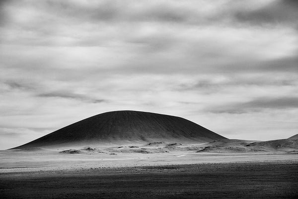 Black and white landscape photograph of an ancient, rounded volcano looming black on the horizon as the daylight goes low on New Mexico, truly the land of enchantment.