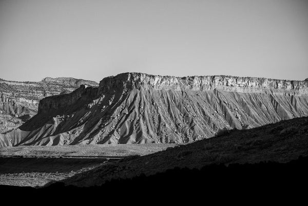 Black and white landscape photograph of a mesa in the Utah desert, captured in the long shadows of early morning.