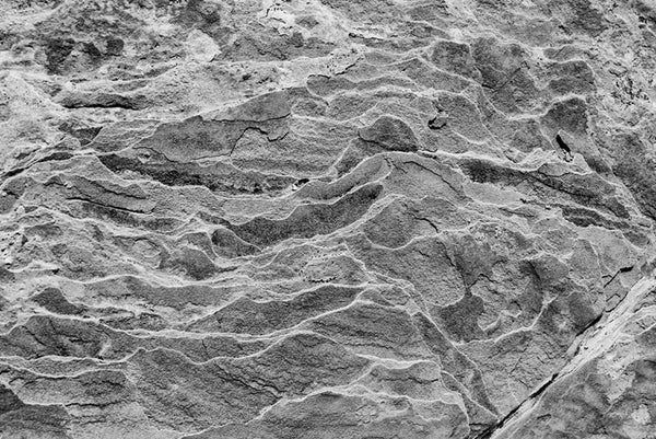 Black and white photograph of layers of brittle sandstone in the desert of Utah. An abstraction from nature featuring rhythmic wave patterns.