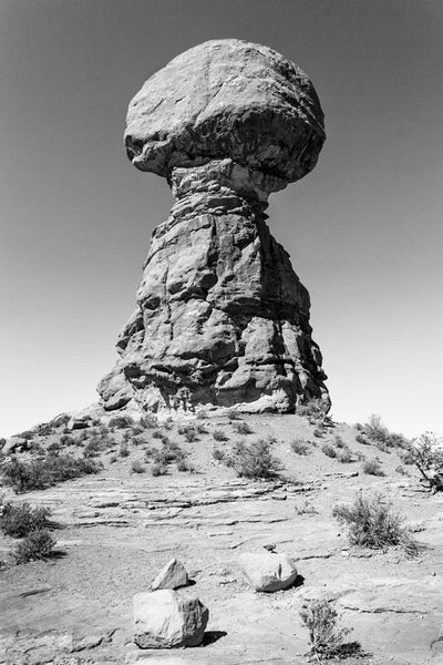 Black and white landscape photograph of a balanced rock atop a stone column in the desert of Utah.