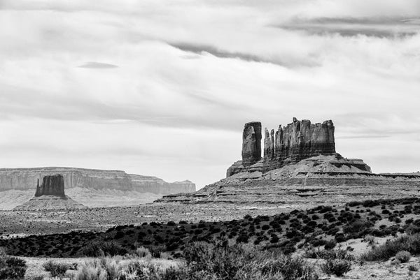 Black and white landscape photograph of giant stone mesas and buttes in Monument Valley, Utah.