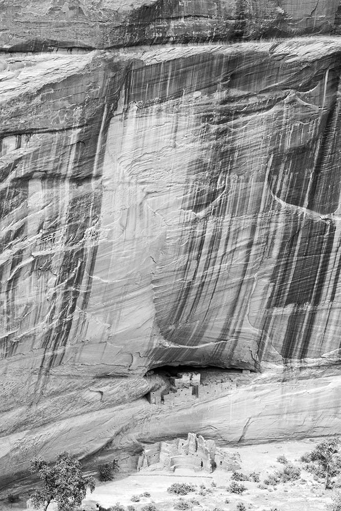 Black and white landscape photograph of the ancient ancestral Puebloan ruins known as the White House ruins in the floor of Canyon de Chelly in Arizona.