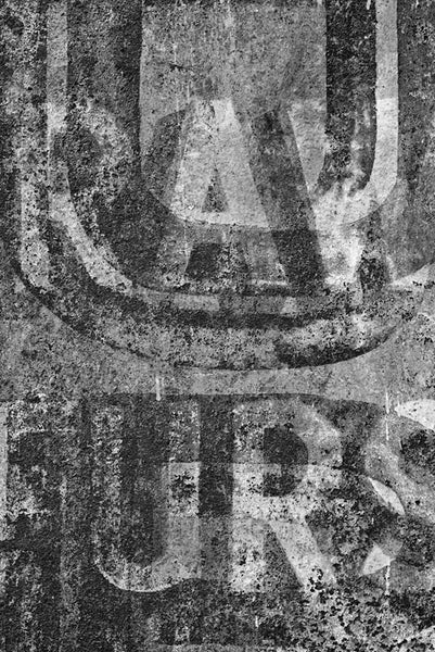 Black and white fine art photograph of the old painted "Raw Furs" signs on the building at 527 Conti Street in the French Quarter of New Orleans, Louisiana. 