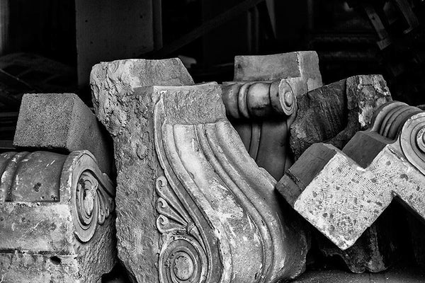 Black and white photograph of a grouping of architectural elements stored in an empty storefront while a building undergoes renovation in downtown Memphis.