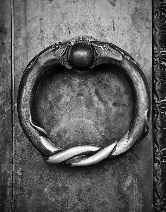 Black and white photograph of the ring of serpents door handles on the huge brass doors at Nashville's Parthenon. Nashville is home to a full-size replica of the Athenian Parthenon, complete with a magnificent 42-foot statue of Athena Parthenos by artist Alan LeQuire. These brass rings can be seen on the exterior doors, which are 24 feet tall, one foot thick, and way 7.5 tons each.