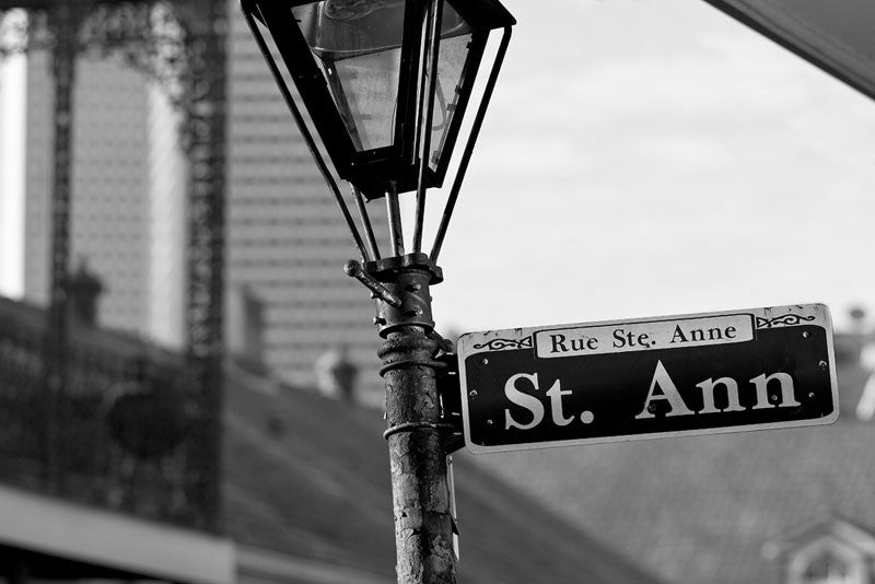 Black and white photograph of a street sign for Rue St. Anne (St. Ann Street) in the New Orleans' French Quarter. 