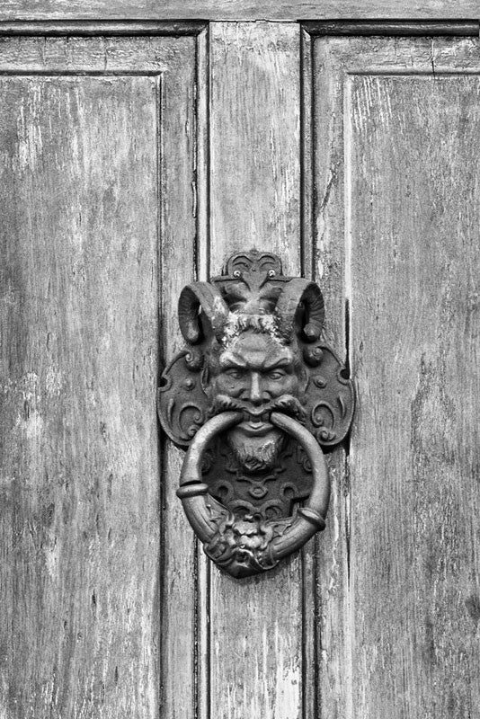 Black and white photograph of an ornate satyr door knocker on a house in the New Orleans' French Quarter. 