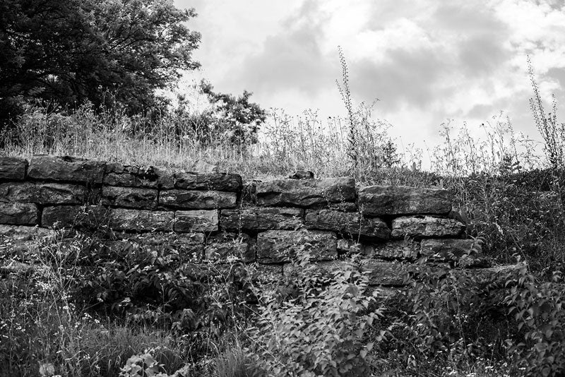 Black and white photograph of the old stone ruins of Fort Negley on a hillside near Nashville. Fort Negley is a star-shaped structure built of limestone blocks on a hilltop south of the city, and was the largest inland fort built during the American Civil War. The fort was built by the Union army in 1862 as a defensive post after the Confederates lost control of Nashville in successive battles, but with fighting concentrated in other areas, the fort never saw action.