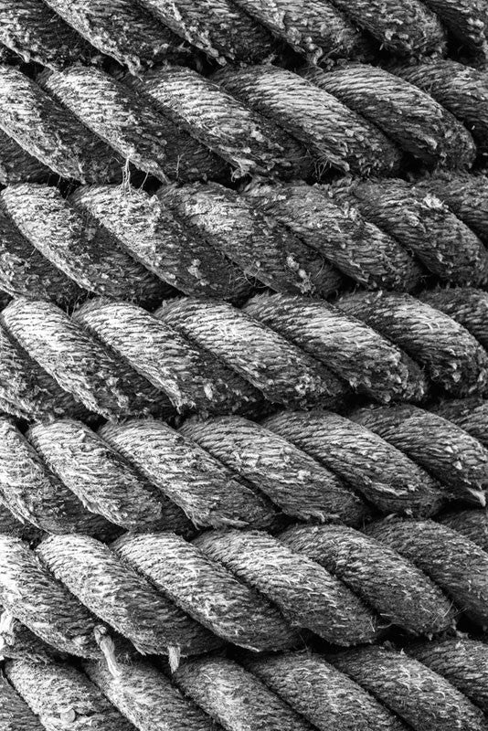Black and white detail photograph of a nautical rope on a marsh pier near the Atlantic Coast.