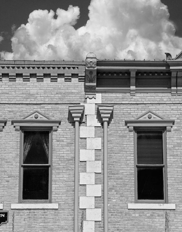 Black and white photograph of a historic architecture on the downtown courthouse square in Georgetown, Texas. The white stone work is reminiscent of a zipper running between two structures.