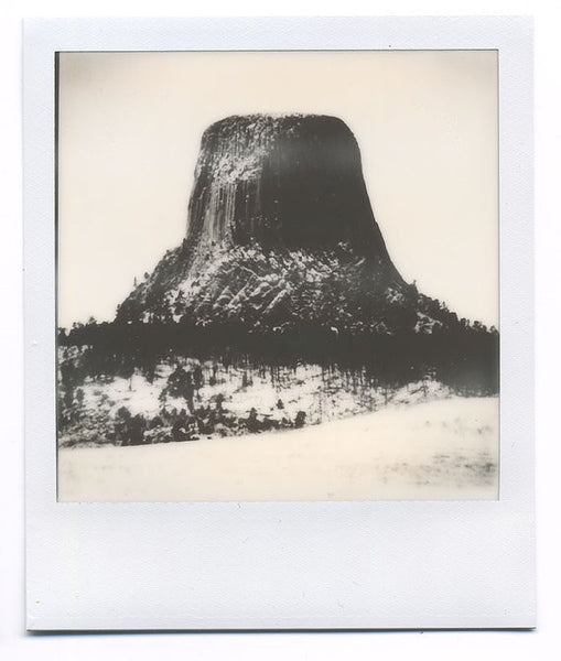 Polaroid-style one-of-a-kind instant photograph of a Wyoming's Devil's Tower surrounded by a winter landscape.  Archivally mounted and matted, and ready to fit an 11″ x 14″ frame. Signed by the artist on back of the print and on the back of the mount. Shot on Impossible Project film, this is a one-of-a-kind, unique photo. The imperfections of the exposure and the way the analog image developed are characteristic of the style of print, and make it imperfectly beautiful.  I've done my best to accurately repre